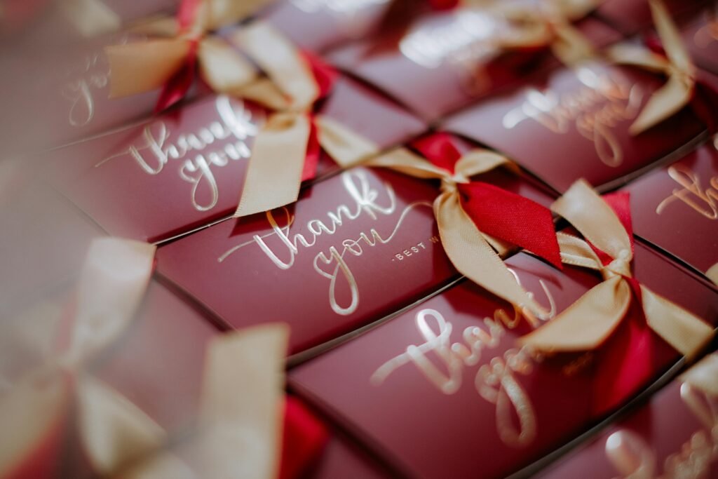 A close-up of beautifully wrapped red gift boxes with 'Thank you' tags and golden ribbons.